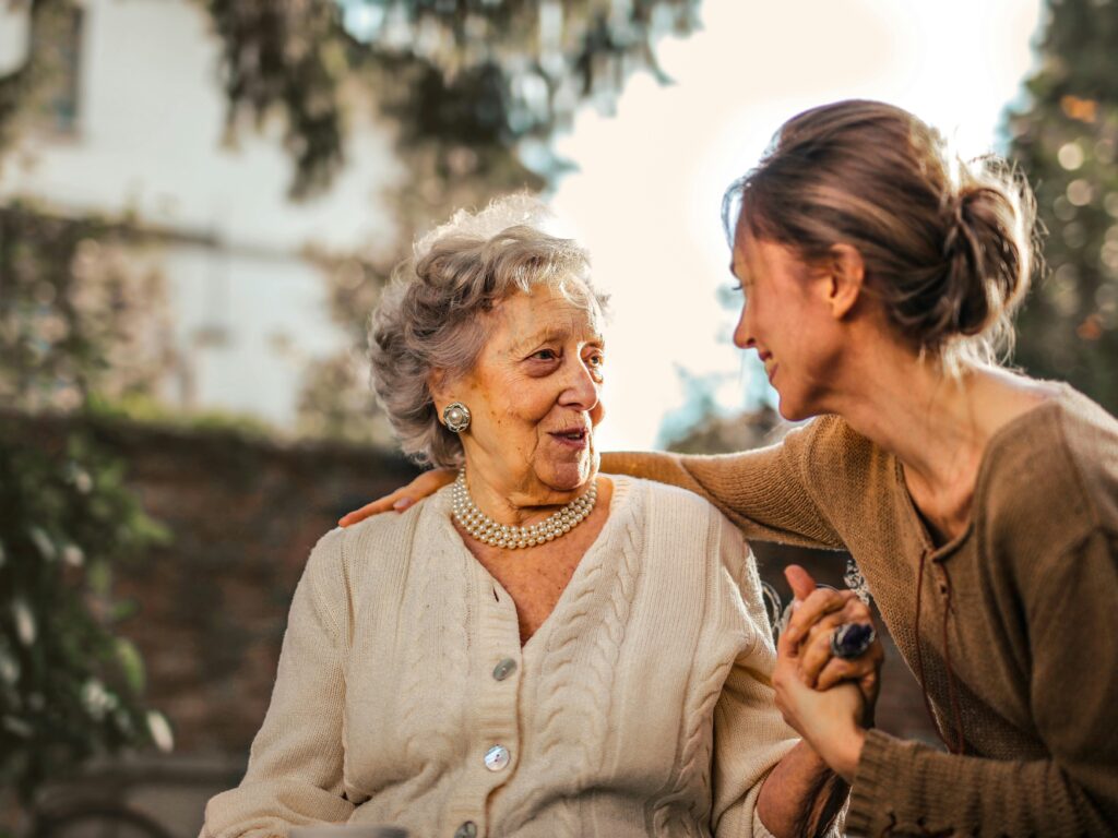 pexels photo 3768131 3768131 Elderly woman and adult daughter share a joyful, affectionate moment in a sunny garden.